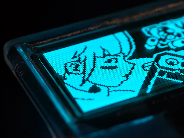 Close macro photograph of the transparent OLED showing a cyan pixel-art character and visible pixel cells.